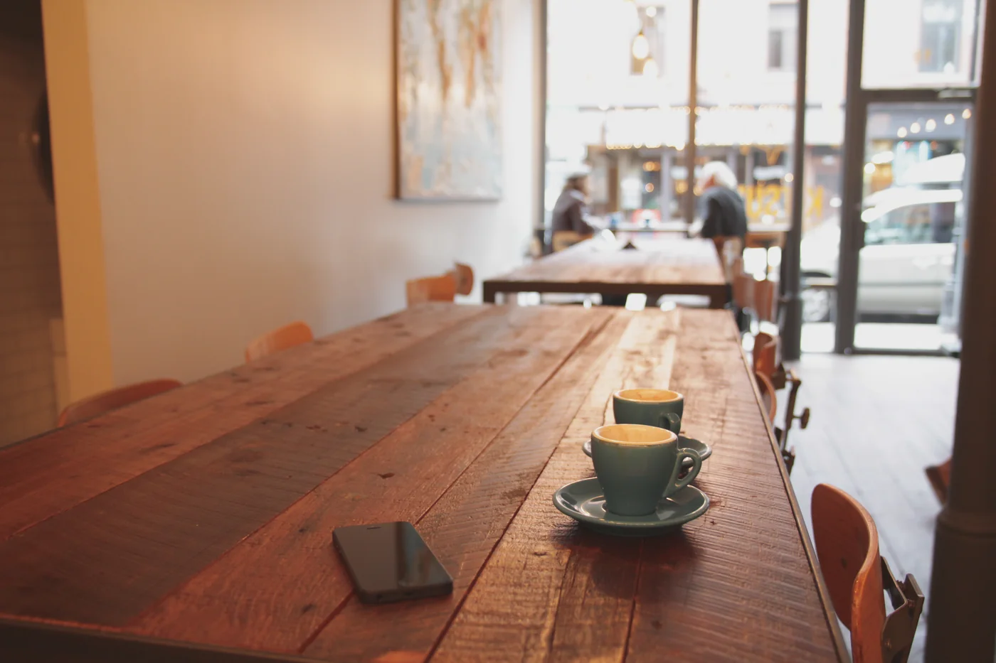Digital menu concept: a smartphone on a café table beside two cups of coffee