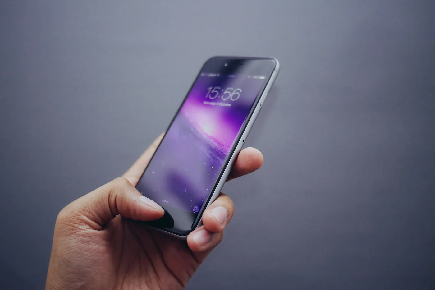 Mobile application concept: a hand holding a smartphone against a plain grey background